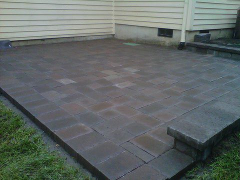 Multiple shades of grey, brown, and red pavers added on patio in the back of a house to gain more usable space while enhancing the look of the back yard.