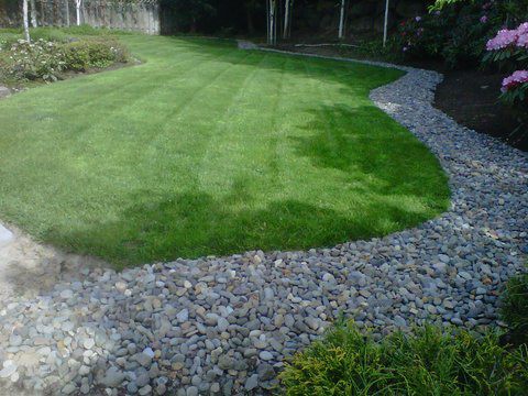 Perfectly mowed backyard with gravel pathway surrounding it.