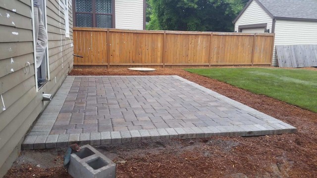Back patio made out of grey and light brick concrete pavers. Perfectly alined forming an aesthetically pleasing square pattern.