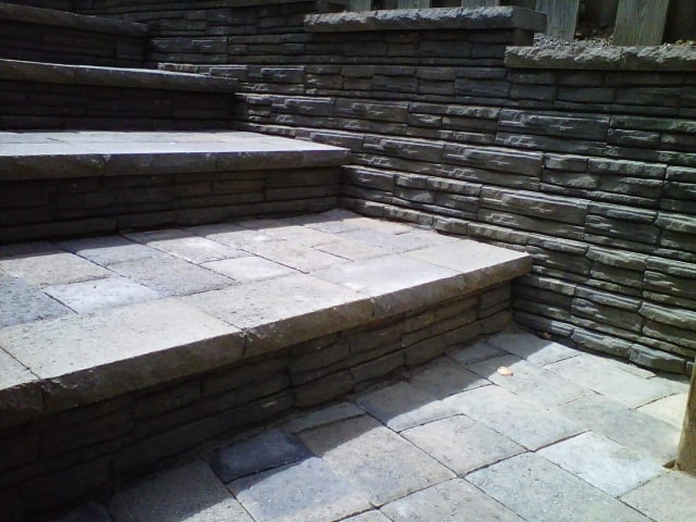 small set of grey stairs made out of concrete brick pavers. in Portland Paver patio, paver patio floor with retaining walls on the right side