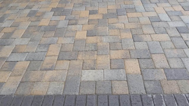 Brick tan and gray paver patio floor with dark gray trimming all around