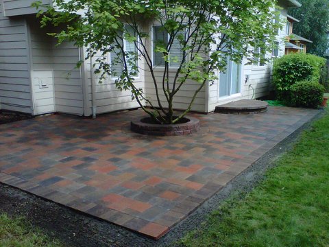 Multiple shades of grey, brown, and red pavers added on patio in the back of a house to gain more usable space while enhancing the look of the back yard.