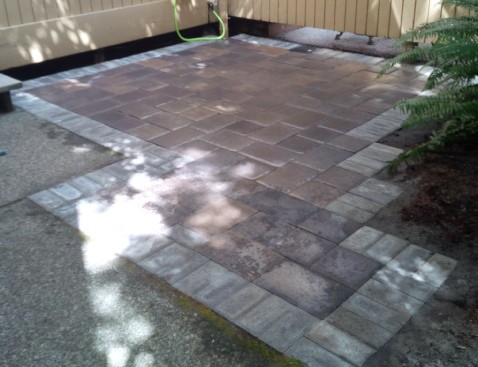 Back patio made out of grey and light brick concrete pavers. Perfectly alined forming an aesthetically pleasing square pattern.